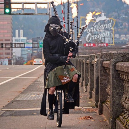 Brian Kidd, a Portland based unipiper, cycling on an unicycle blowing flaming bagpipers dressed as Darth Vader from Star Wars. Star Wars the last jedi tribute