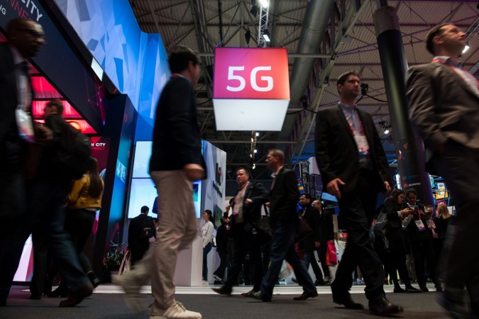 Visitors walk under a 5G logo hanging from the ceiling on the second day of the Mobile World Congress on February 28, 2017, in Barcelona. 5G mobile communication