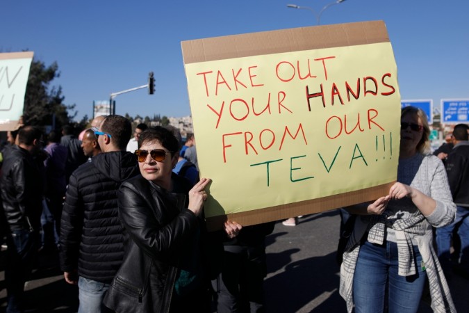 Israeli employees of Teva, the world's biggest manufacturer of generic drugs, hold placard during a protest in the centre of Jerusalem on December 17, 2017 Teva