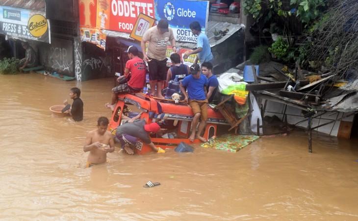 Residents are seen on the top of a partially submerged vehicle along a flooded road in Cagayan de Oro city in the Philippines. Philippines