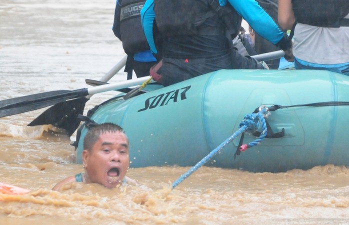 A man clings onto the rope of a rescue boat as residents are evacuated from their homes due to heavy flooding in Cagayan de Oro city in the Philippines Philippines