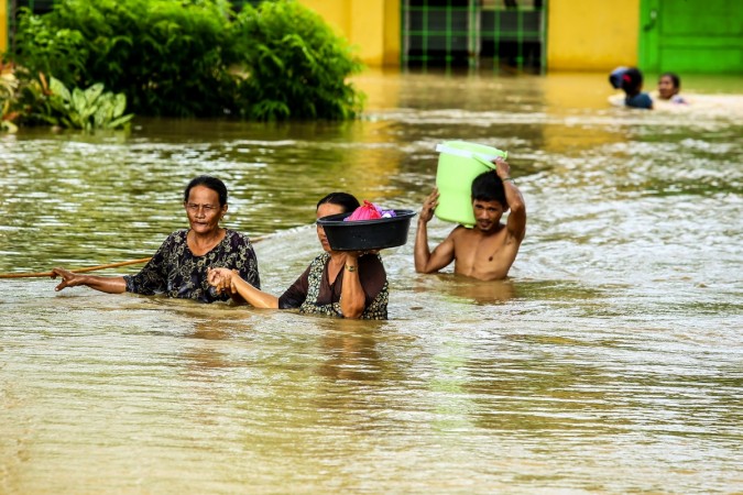 Residents walk through floodwaters as they evacuate to a safer place in Kabacan, North Cotabato, on the southern island of Mindanao on December 23 Philippines
