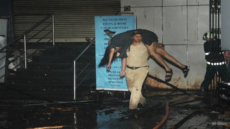 A constable carries a body outside the Kamala Mills Compound after major fire killed 14. kamala deaths