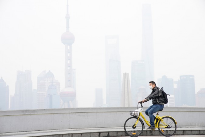 A man wearing a face mask rides a bicycle on a bridge in front of the financial district of Pudong covered in smog during a polluted day in Shanghai, China November 22, 2017. China air pollution