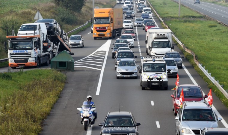 Members of the CGT national trade union, escorted by a motorcycle policeman (L) and a police van (C-R), wave their union's flags as they take part in a slow down traffic operation on September 25, 2017. FRANCE-POLITICS-LABOUR-LAW-TRANSPORT-PROTEST