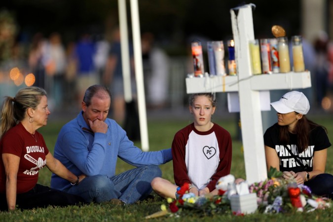 A family sits around one of 17 crosses at a memorial for the victims of the shooting at Marjory Stoneman Douglas High School in Parkland, Florida, U.S. February 16, 2018. florida shooting
