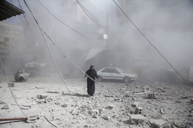 A woman gestures as she walks on rubble of damaged buildings after an airstrike in the besieged town of Douma in eastern Ghouta. syria