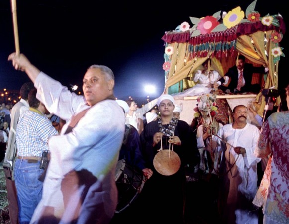 An Egyptian traditional dancer dances in front of a camel carrying one of 250 couples on their mass wedding ceremony. Egyptian wedding