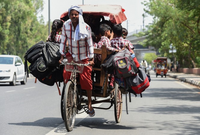 Indian school children travel on an over-loaded rickshaw on their way back home after their school in New Delhi on May 4, 2018. Delhi
