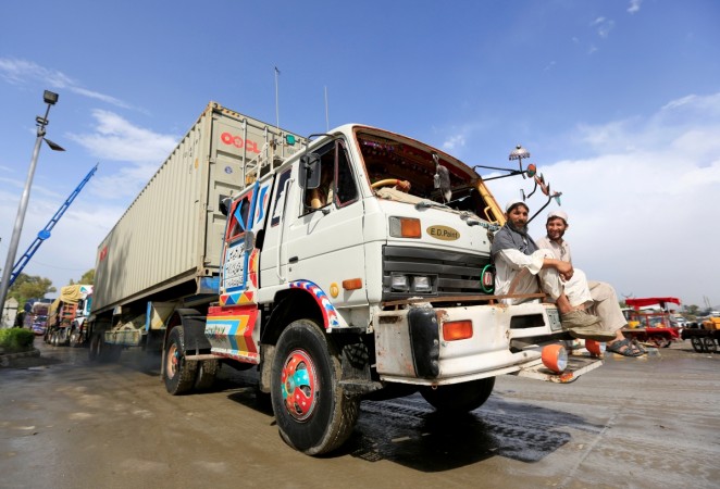 Afghan men sit in front of supply trucks carrying containers for export at the Customhouse in Jalalabad, Afghanistan May 14, 2018. picture taken May 14, 2018. Afghanistan