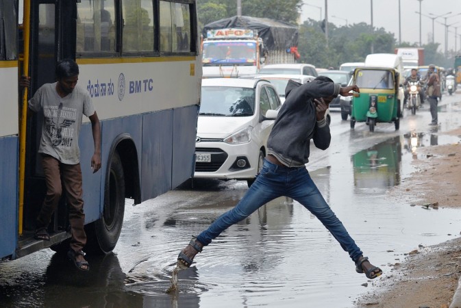 An Indian pedestrian jumps a puddle of water as he crosses the road after copious rains in Bangalore An Indian pedestrian jumps a puddle of water as he crosses the road after copious rains in Bangalore