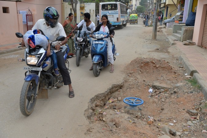 In this photograph taken on November 1, 2017, motorists ride past a pothole created during road repair work in Bangalore. INDIA-TRANSPORT-TECHNOLOGY