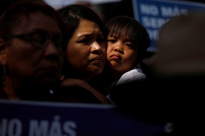 A child embraces a woman as people hold signs to protest against U.S. President Donald Trump's executive order to detain children crossing the southern U.S. border and separating families outside of City Hall in Los Angeles, California, U.S. June 7, 2018. A child embraces a woman as people protest against Trump