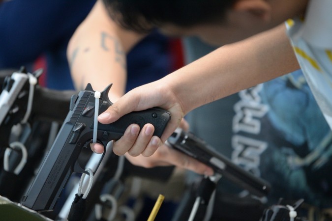 Visitors examine handguns for sale during the opening of the annual gun show in Manila Visitors examine handguns for sale during the opening of the annual gun show in Manila