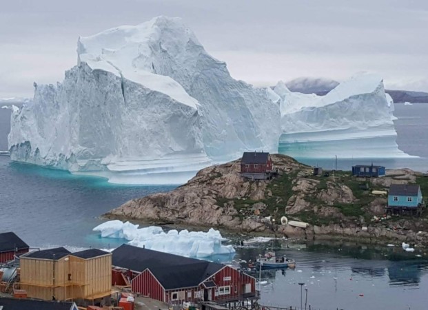 A giant iceberg is seen behind an Innaarsuit settlement, Greenland A giant iceberg is seen behind an Innaarsuit settlement, Greenland