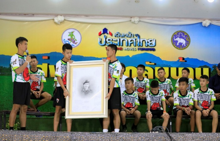   The boys who were rescued from a flooded cave hold a portrait of the former Navy SEAL diver Saman Kunan 