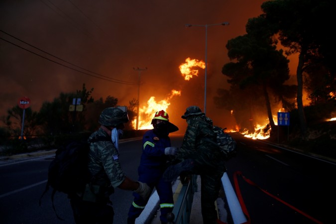 Firefighters and soldiers fall back as a wildfire burns in the town of Rafina, near Athens, Greece wildfire