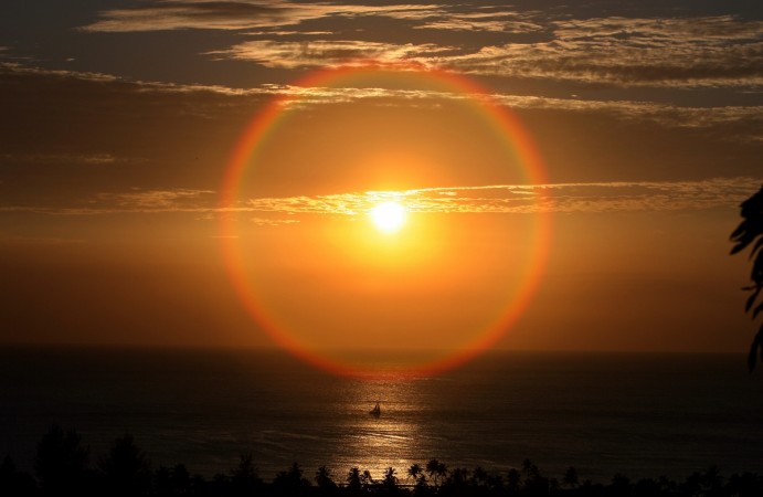 A yacht sails near the shore as the sun sets ending a day in Antigua Antigua