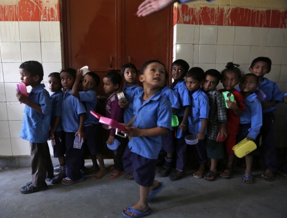 School boys carry their tiffin boxes as they wait to receive the free mid-day meal, distributed by a government-run primary school, in New Delhi July 19, 2013. Midday meals students