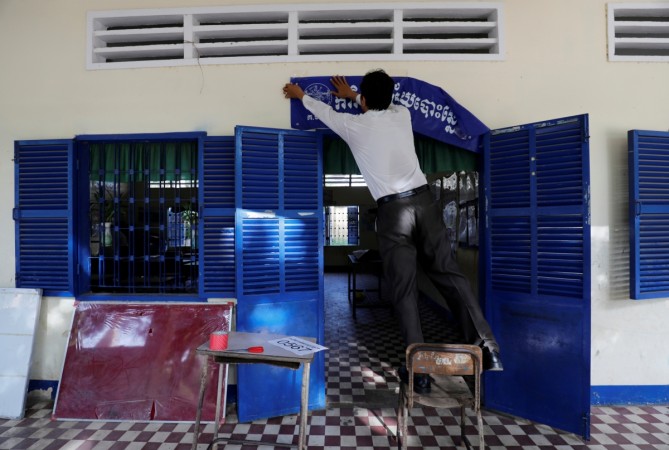 An election worker hangs a banner which reads An election worker hangs a banner outside a classroom at a school in Phnom Penh