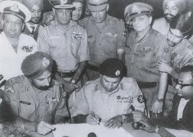 In picture: Lt Gen Niazi signs the Instrument of Surrender under the gaze of Lt Gen Aurora, essentially declaring independence for Bangladesh. Standing immediately behind from L to R: Vice Admiral Krishnan, Air Marshal Dewan, Lt Gen Sagat Singh, Maj Gen JFR Jacob (with Flt Lt Krishnamurthy peering over his shoulder). Veteran newscaster Surojit Sen of All India Radio is seen holding a microphone on the right. Bangladesh Liberation War