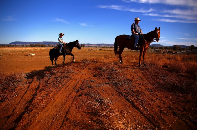 Farmer Scott Cooper and his daughter Charlie ride their horses along a fence in a drought-effected paddock on their property named Australia drought
