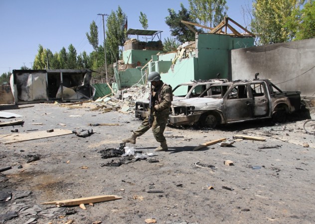 A member of the Afghan security forces stands guard next to damaged army vehicles after a Taliban attack in Ghazni city, Afghanistan August 15, 2018. Taliban attack