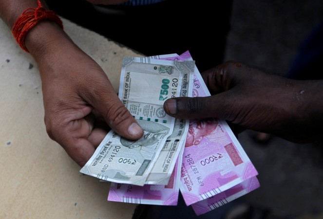 A customer hands Indian currency notes. rupee
