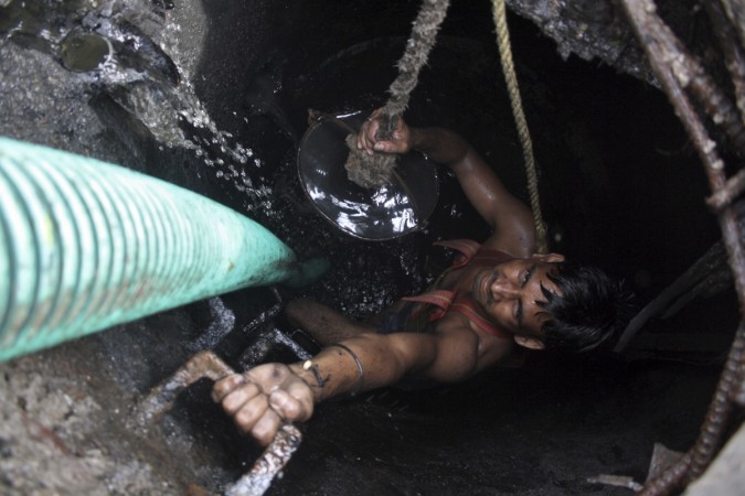 A labourer cleans an underground sewer. Manual scavenger