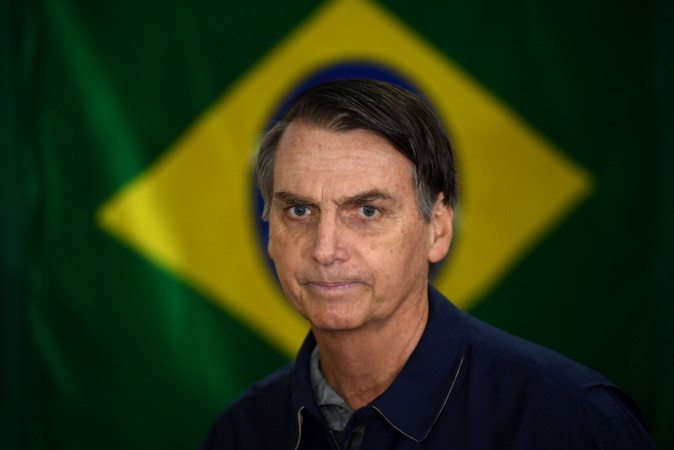 air Bolsonaro walks in front of the Brazilian flag as he prepares to cast his vote during the general elections, in Rio de Janeiro, Brazil, on October 7, 2018 Jair Bolsonaro