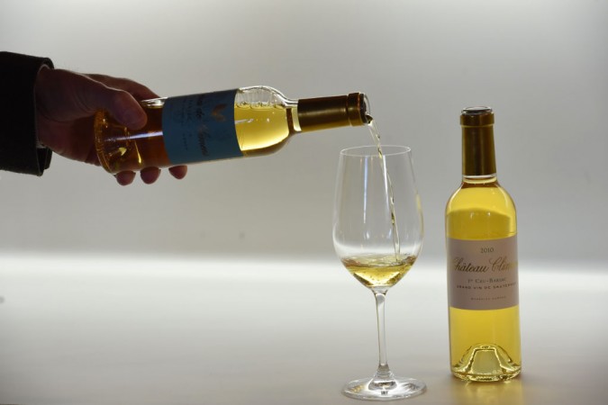 A man pour a glass of a 2010 Chateau Climens 1er Cru-Barsac white wine. English white wine
