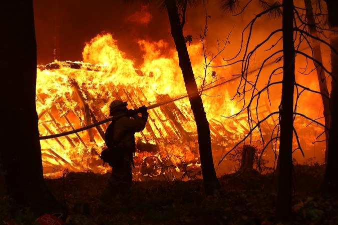 A Cal Fire firefighter sprays water on a home next to a burning home as the Camp Fire moves through the area on November 9, 2018 in Magalia, California. Fueled by high winds and low humidity, the rapidly spreading Camp Fire ripped through the town of Paradise and has quickly charred 70,000 acres and has destroyed numerous homes and businesses in a matter of hours. The fire is currently at five percent containment california wildfire