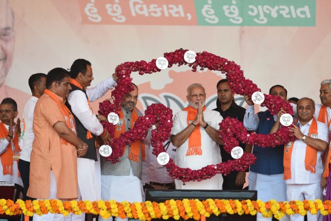 Indian Prime Minister Narendra Modi (C/R) gestures while being garlanded in rose petals in the formation of a map of Gujarat State during Gujarat Gaurav Mahasamellan at Bhaat village on the outskirts of Ahmedabad on October 16, 2017. narendra modi