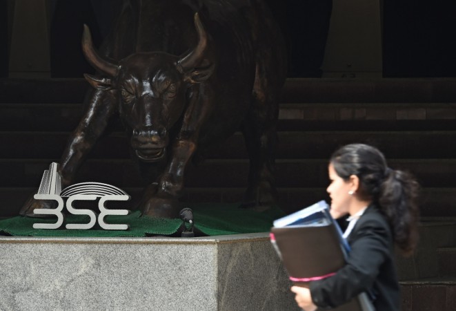 An Indian woman speaks on her phone while walking past a Bull sculpture outside the Bombay Stock Exchange (BSE) in Mumbai on February 6, 2018. Asian stocks plunged on February 6 after a record-breaking loss on Wall Street, extending a global rout as panicked investors fret over rising US borrowing costs and take profits after months of market euphoria. Bombay Stock Exchange