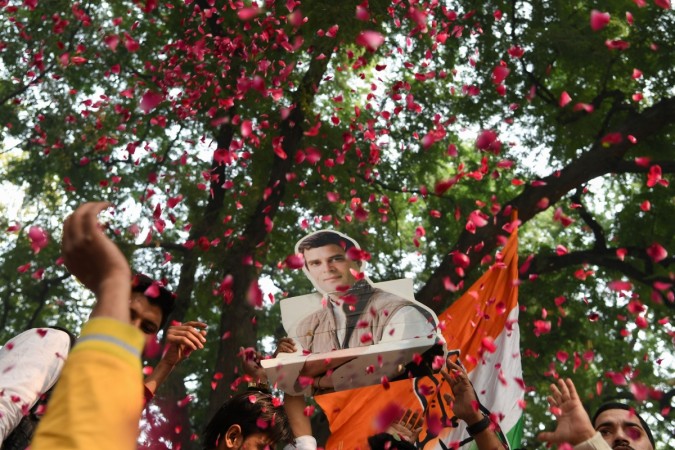 A bust placard of All India Congress Committee (AICC) President Rahul Gandhi is seen through a shower of rose petals as Congress party supporters celebrate outside the party headquarters in New Delhi on December 11, 2018, as vote counting in five Indian states began. - Counting of votes in five Indian states began on December 11 as the country's ruling Bharatiya Janata Party engaged in close contest with opposition Congress party in three key states, a test for Prime Minister Narendra Modi's popularity ahead of the general election. A bust placard of All India Congress Committee (AICC) President Rahul Gandhi