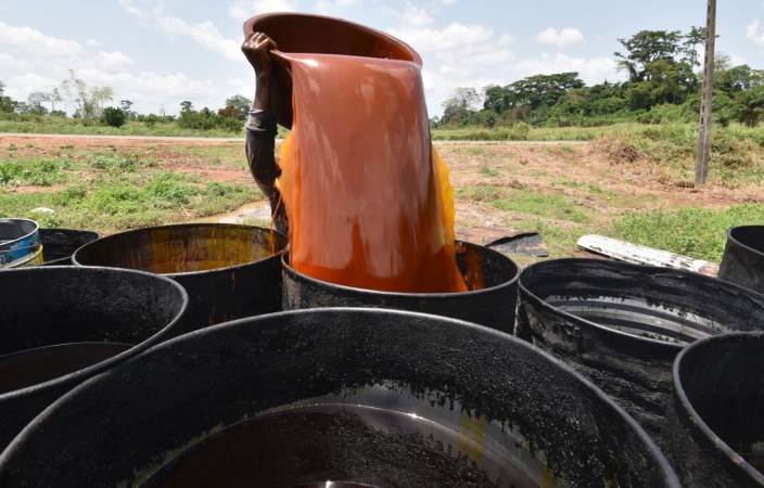 A woman pours a container of palm oil into a barrel at an artisinal workshop on March 7, 2017 in Divo. Ivory Coast is the world's leading producer of cashew nuts and cola, along with cocoa. It also leads the field in Africa for banana growing and takes second place for palm oil and third place for cotton and coffee. / AFP PHOTO / Sia KAMBOU A woman pours a container of palm oil into a barrel at an artisinal workshop on March 7, 2017 in Divo
