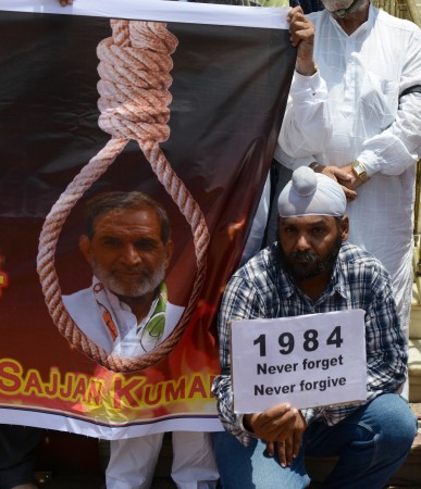 An Indian Sikh holds a placard as he sits alongside a poster depicting the image of Congress leader Sajjan Kumar during a rally seeking justice for the massacre of Sikhs following the 1984 assassination of then Indian prime minister Indira Gandhi, near the Gurudwara Gobind Dham in Ahmedabad on June 2, 2013. Activists accuse Congress of having turned a blind eye to the killing of Sikhs and say some of its leaders may have helped incite mobs. AFP PHOTO / Sam PANTHAKY INDIA-POLITICS-PROTEST-SIKH
