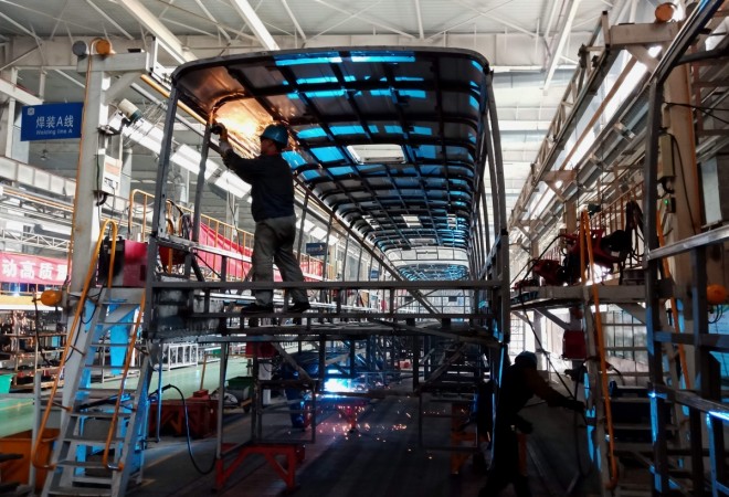 This photo taken on December 12, 2018 shows workers building an electric bus at a factory in Liaocheng, in China's eastern Shandong province. - Chinese consumer spending grew at its slowest pace in 15 years and factories eased up in November, official data showed on December 14, raising the prospect of fresh stimulus measures as the economy sputters. (Photo by STR / AFP) / China OUT CHINA-ECONOMY