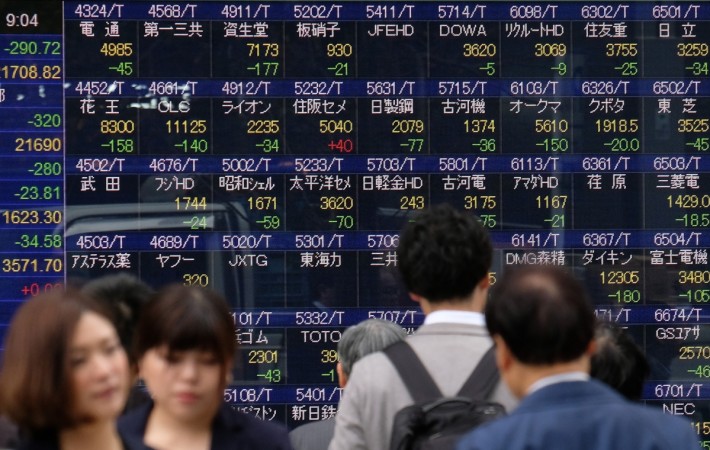 Pedestrians walk past a stock indicator board of the Tokyo Stock Exchange in Tokyo on December 5, 2018. - Tokyo stocks opened lower on December 5, following a plunge on Wall Street on worries about US economic growth and with investors cautious ahead of key US jobs data. (Photo by Kazuhiro NOGI / AFP) JAPAN-STOCKS