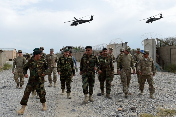 In this photograph taken on August 13, 2015, US army and Afghan National Army (ANA) soldiers walk as a NATO helicopter flies overhead at coalition force Forward Operating Base (FOB) Connelly in the Khogyani district in the eastern province of Nangarhar. US army and Afghan National Army