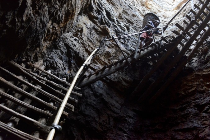 In this photograph taken on January 31, 2013, a miner slowly carries a heavy load of wet coal on a basket hundreds of feet up on wooden slats that brace the sides of a deep coal mine shaft near Rimbay village in the Indian northeastern state of Meghalaya. Thousands of private mines employ slim men and boys that will fit in thin holes branching out from deep shafts dug out from the ground in the East Jaintia Hills in Northeastern Indian state of Meghalaya. This state is the only state in India where coal mining is done privately by mine owners, who use cheap labour to supply the demand for this energy resource. Accidents and quiet burials are commonplace, with years of uncontrolled drilling making the rat-hole mines unstable and liable to collapse at any moment. After decades of unregulated mining, the state is due to enforce its first-ever mining policy later this year. meghalaya mines