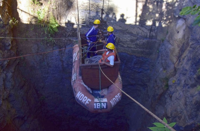 In this photo taken on December 30, 2018, Indian Navy divers go down in the mine with a pulley during rescue operations after 15 miners were trapped by flooding in an illegal coal mine in Ksan village in Meghalaya's East Jaintia Hills district of India. - Indian Navy and NDRF personnel went inside a 370-foot-deep mine, where 15 miners are trapped, to ascertain the water level inside on December 30, officials said. meghlaya miners rescue