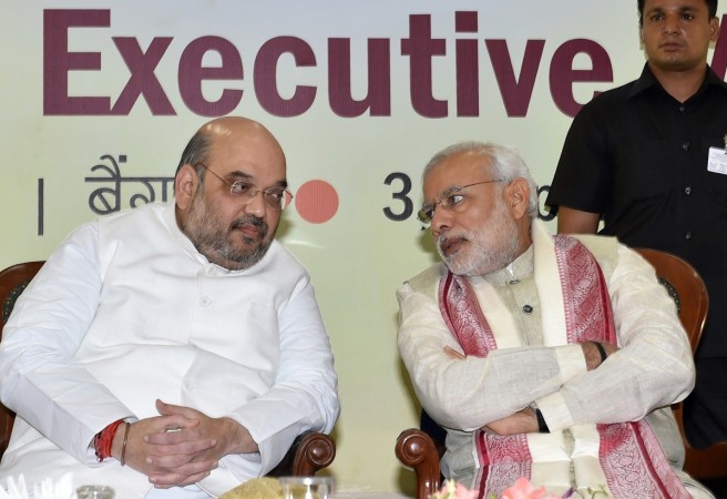 Indian Prime Minister Narendra Modi (R) and Bharatiya Janata Party (BJP) National President Amit Shah speak at a BJP National Executive committee meeting in Bangalore on April 3, 2015. modi amit shah