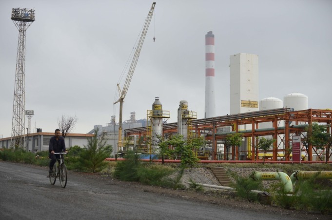 A man cycles by an oil refinery belonging to Essar Oil at Vadinar, some 380km from Ahmedabad on October 4, 2016. With the chances of international crude price hitting $100 a barrel and remaining there for a long time, the new government taking over after the Lok Sabha elections will have an uphill task to manage the economy. a worker cycling by an Indian oil refinery