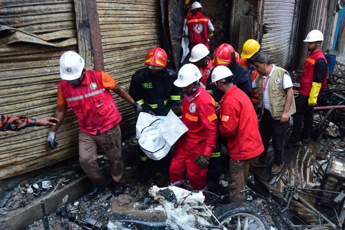 Rescue personnel carry the body of a victim after a fire broke out in Dhaka on February 21, 2019. - At least 69 people have died in a huge blaze that tore through apartment buildings also used as chemical warehouses in an old part of the Bangladeshi capital Dhaka, fire officials said on February 21, 2019. dhaka fire