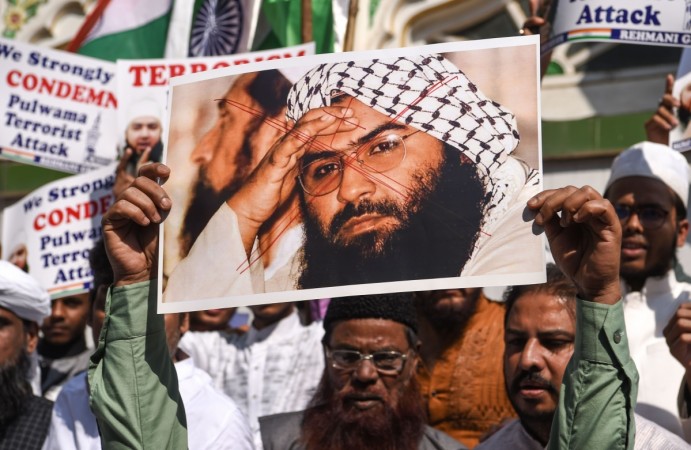 Indian Muslims hold a scratched photo of Jaish-e-Mohammad group chief, Maulana Masood Azhar, as they shout slogans against Pakistan masood azhar
