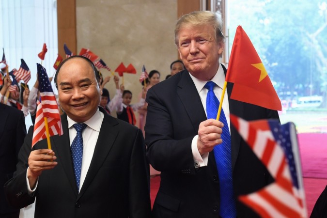 US President Donald Trump (R) holds a Vietnamese flag as Vietnam's Prime Minister Nguyen Xuan Phuc (L) waves a US flag upon their arrival for a meeting at the Government Office in Hanoi on February 27, 2019, Trump in Hanoi