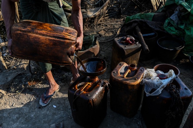 This photo taken on March 10, 2019 shows a worker filling containers with crude oil at an informal oil field in Minhla township, central Myanmar. - The fields near Minhla are Myanmar's equivalent of the old American Wild West, where informal oil entrepreneurs scramble from site to site in the hope of drilling deep and striking lucky. a worker filling containers with crude oil at an informal oil field in Minhla township, central Myanmar