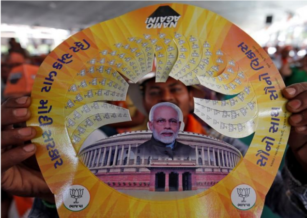 A supporter of Prime Minister Narendra Modi displays a paper cap with images of Modi and Indian Parliament during an election campaign rally in Junagadh, Gujarat. Narendra Modi