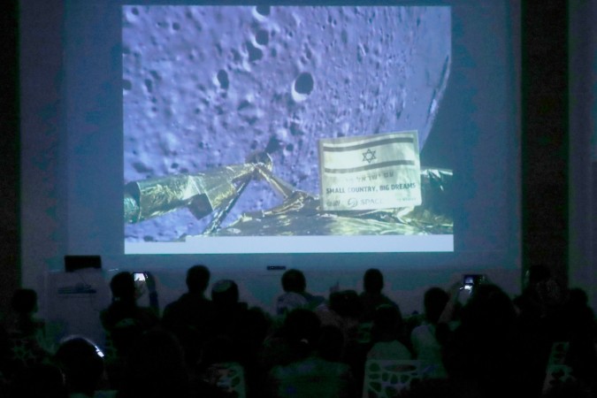 People watch a screen showing a picture taken by the camera of the Israel Beresheet spacecraft of the moon surface as the craft approaches and before it crashed during the landing at the 'Planetaya Planetarium' in the Israeli city of Netanya, on April 11, 2019. Israel Beresheet spacecraft
